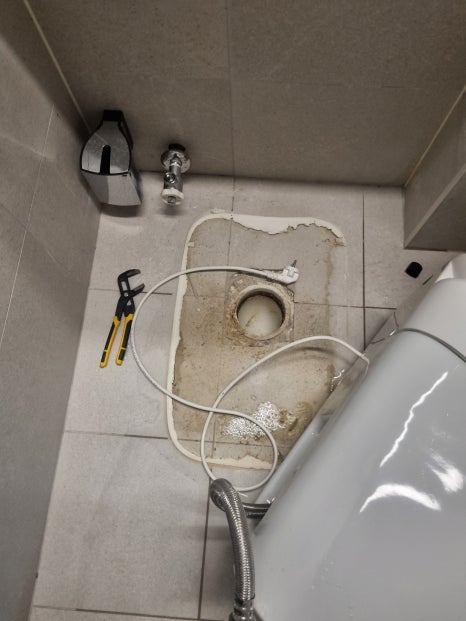 화장실 바닥에 작업 도구를 놓고 변기 상태를 살피는 모습