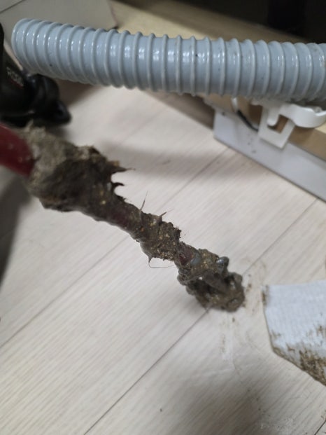분리한 주름관 안쪽에 검은 기름 찌꺼기가 붙어 있는 모습