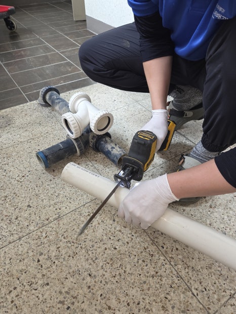 전동 드릴로 배관 이음쇠를 조립하는 모습