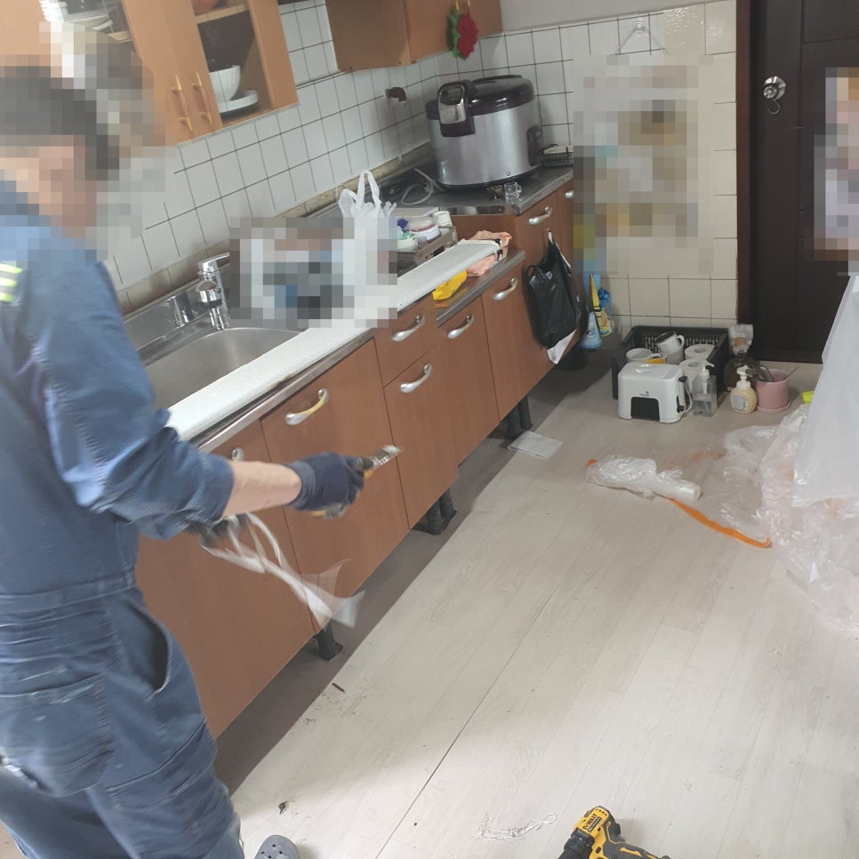 주방 싱크대 아래쪽 배관을 살펴보는 모습